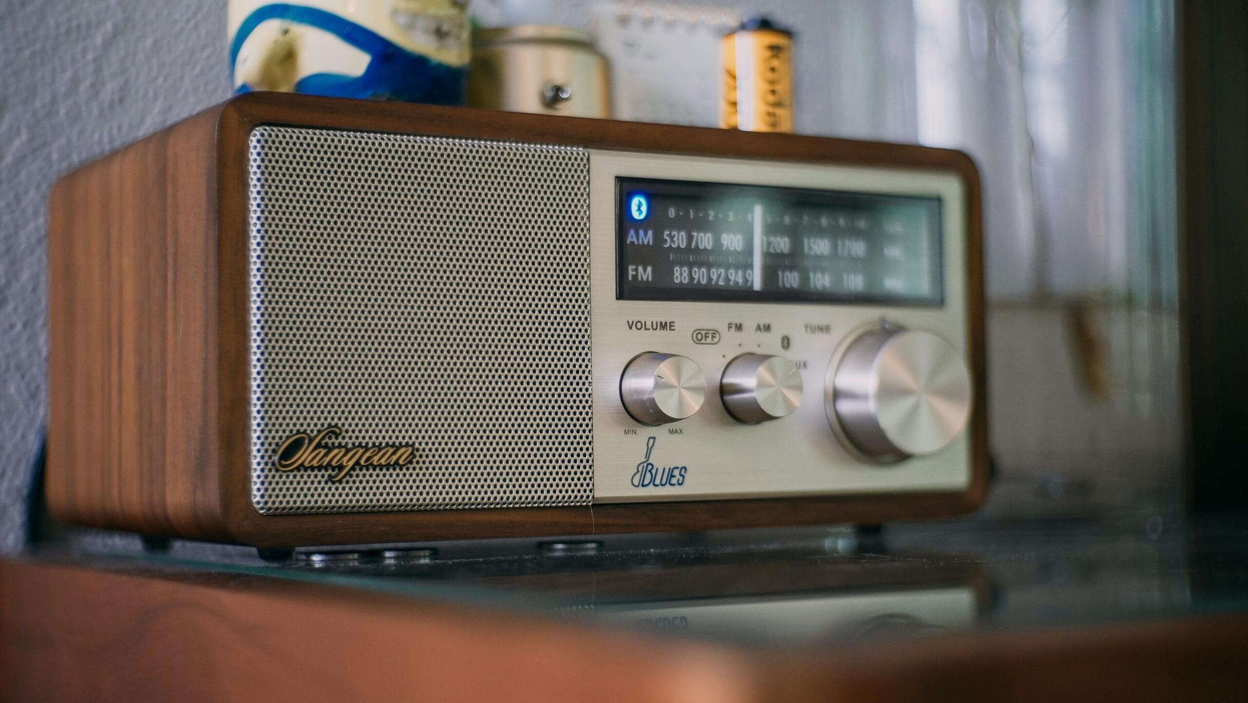 Retro drveni radio aparat sa srebrnim dugmadima i prijemnikom postavljen na stol