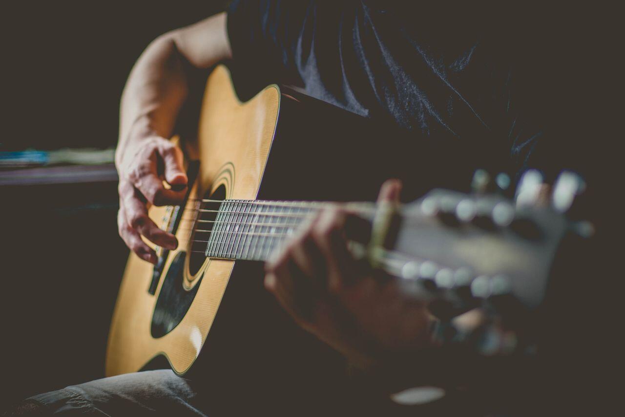 homme grattant ses cordes de guitarre
