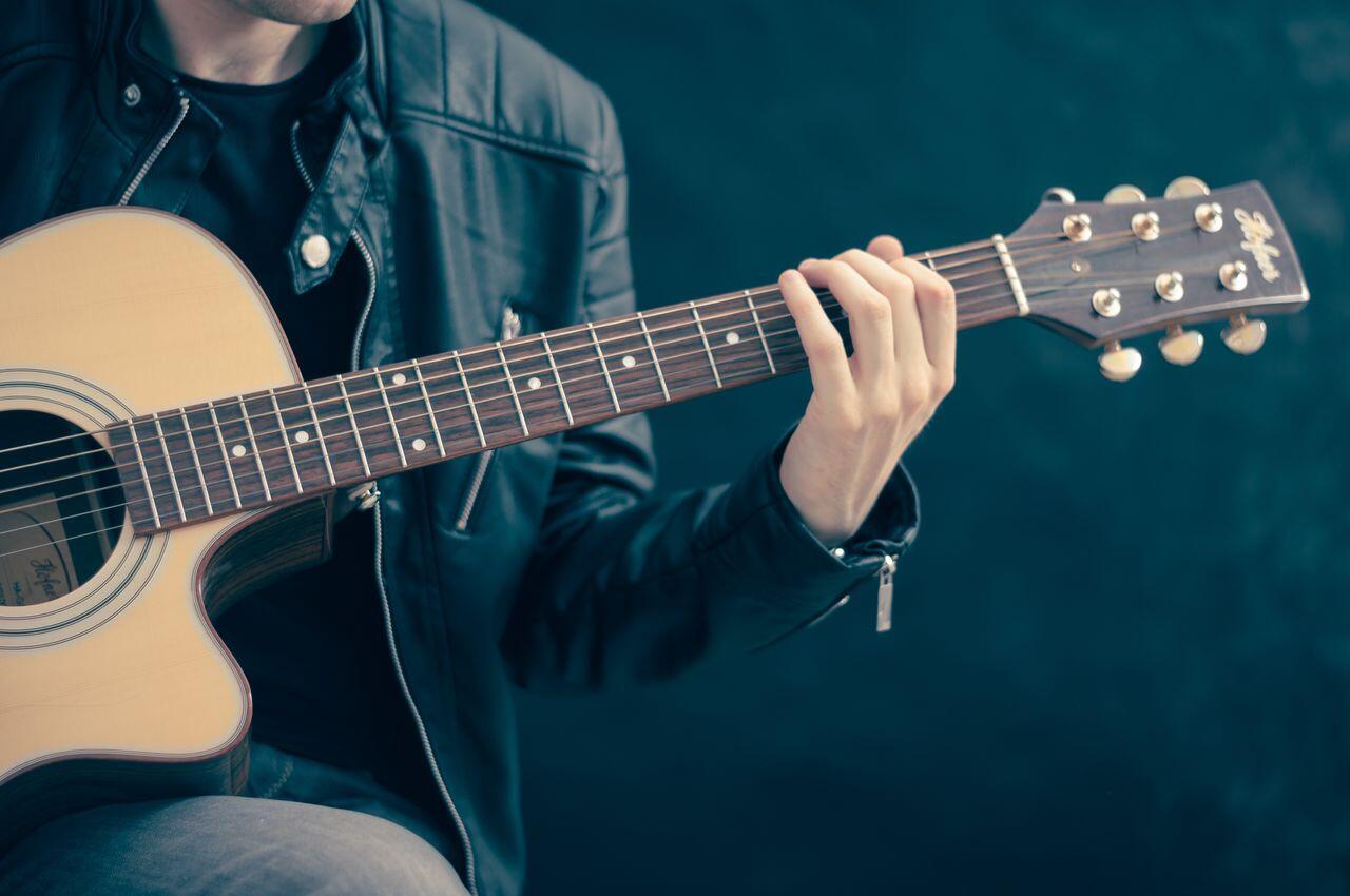 homme en blouson de cuir assis jouant de sa guitare