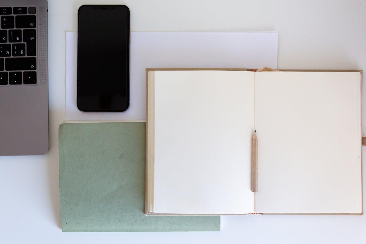 carnets crayon telephone et ordinateur sur une table