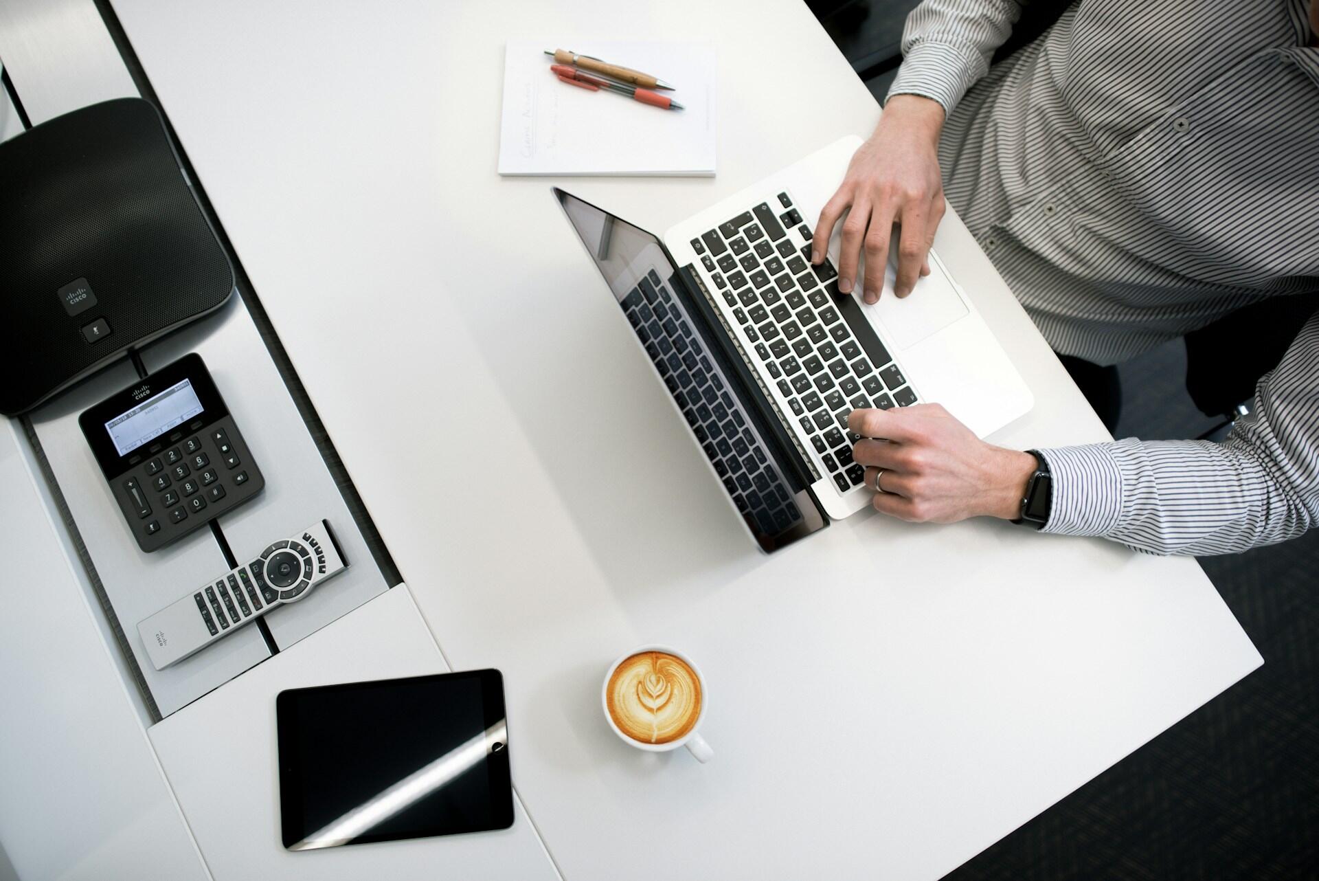 homme au bureau avec chemise sur ordi avec cafe et calculette