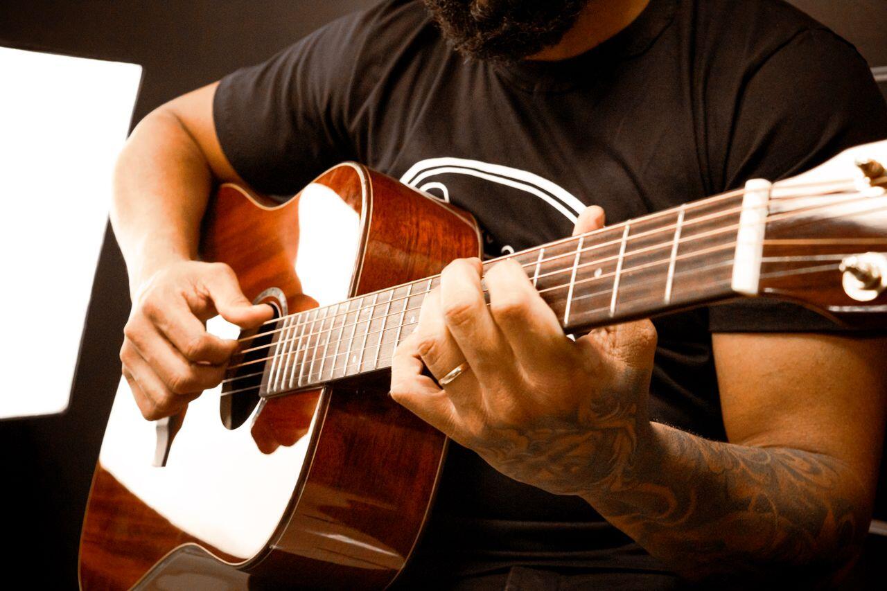 homme en tee shirt noir jouant de la guitare