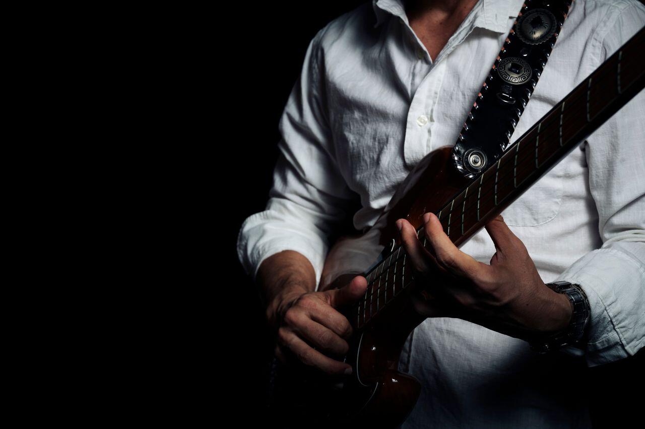 homme a chemise assis avec sa guitare