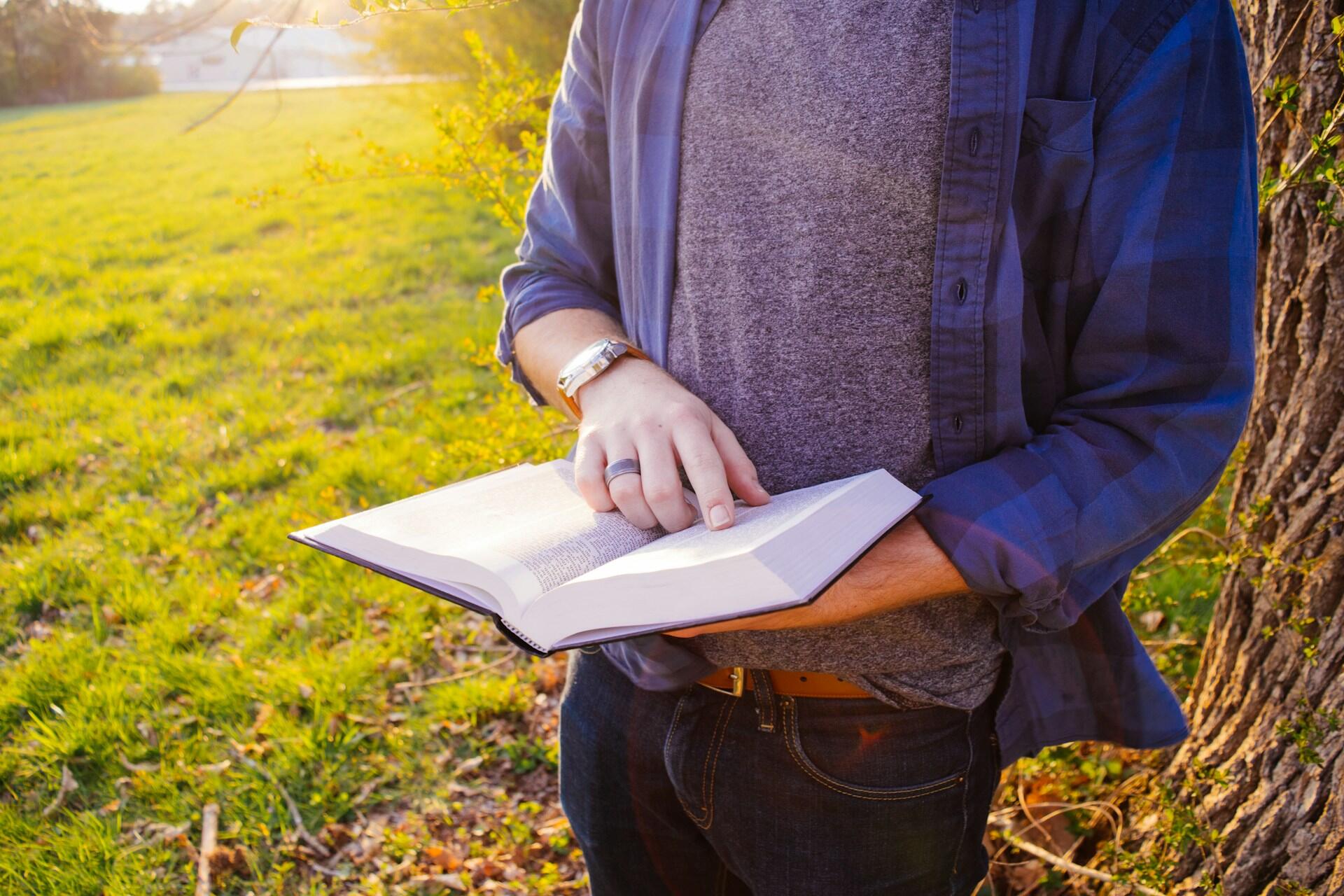 jeune homme dehors etudiant un livre