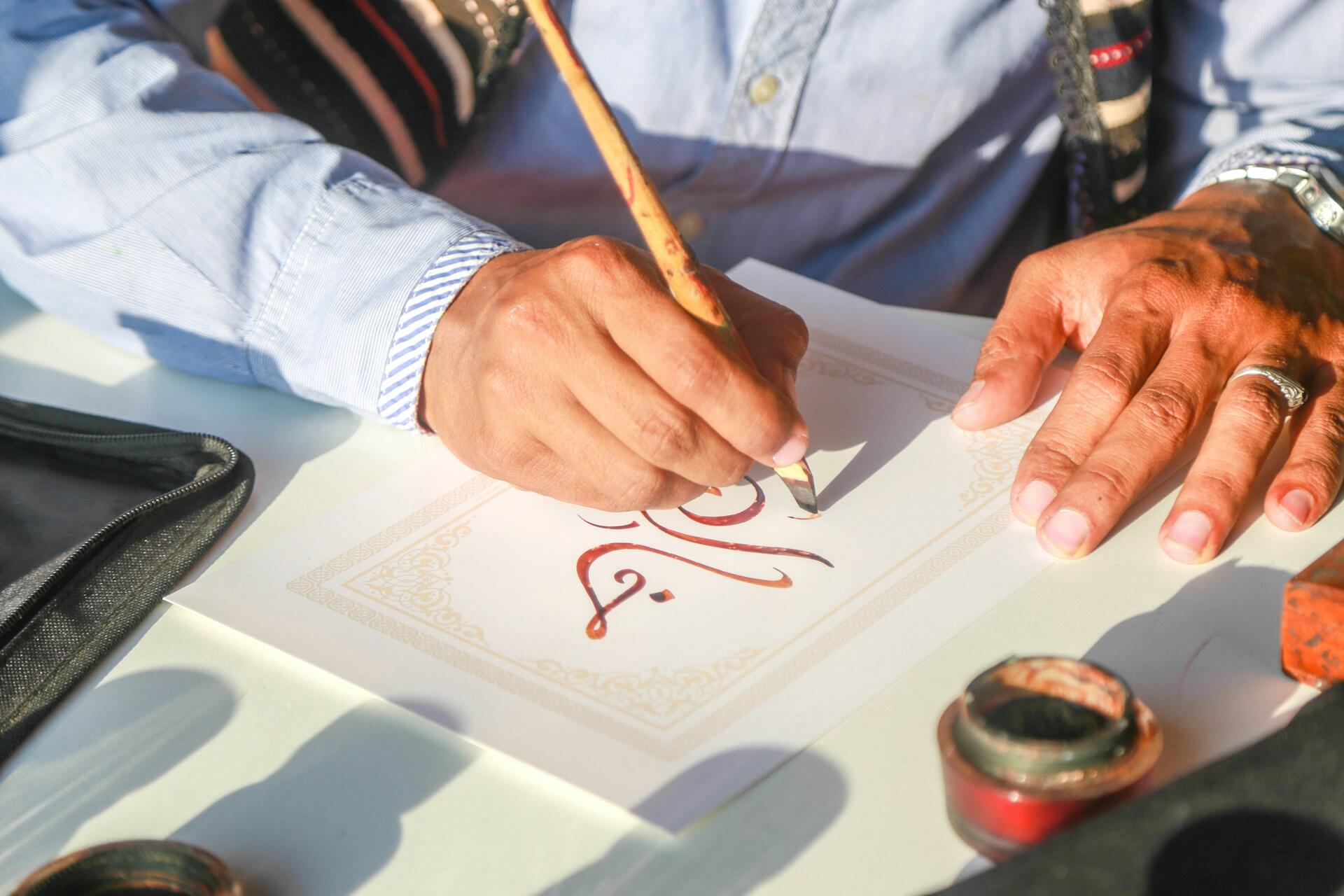 homme effectuant une calligraphie arabe