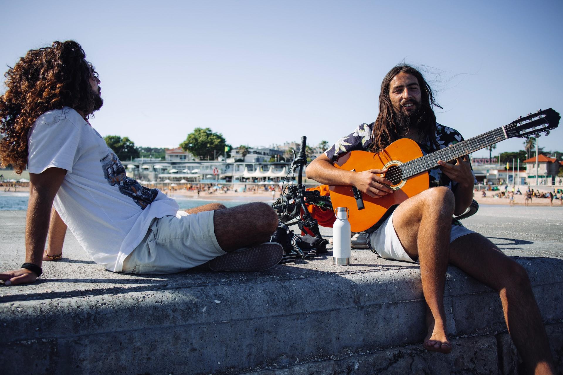 deux hommes avec une guitare devant un fleuve