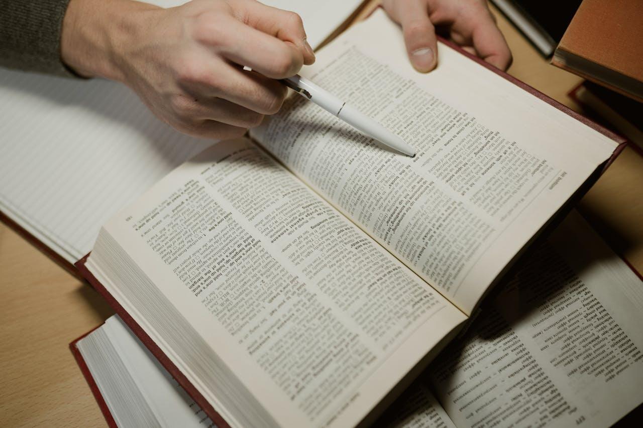 main avec un stylo ouvert sur un dictionnaire