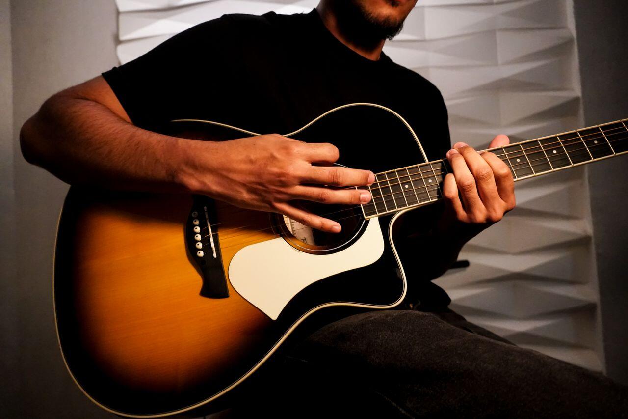 homme en tee shirt noir jouant de la guitare