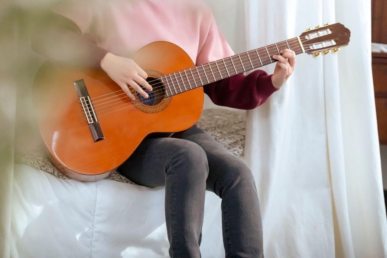 femme en rose assise avec sa guitare
