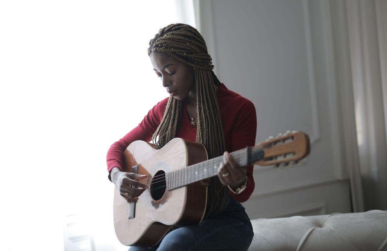 femme en rouge chez elle concentree avec sa guitare