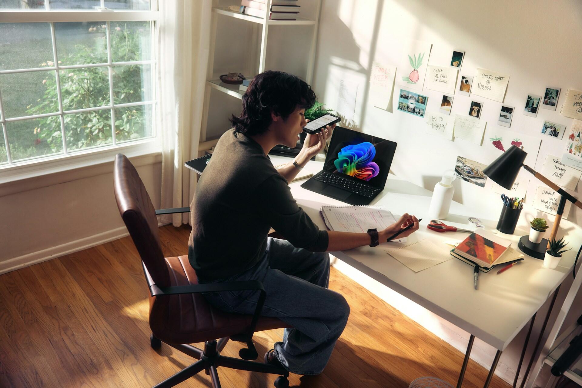 jeune dans sa chambre travaillant a son bureau avec son laptop et un cahier