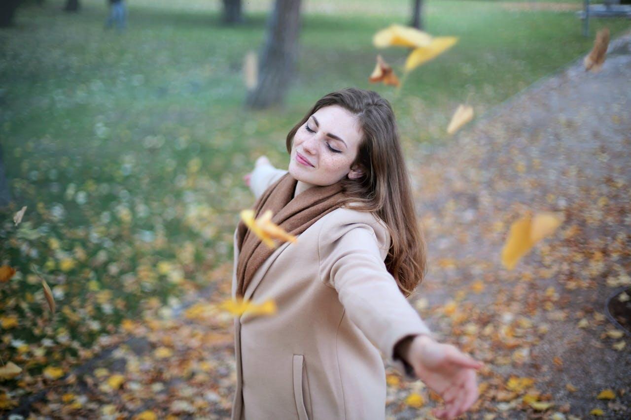 jeune femme heureuse feuilles au vent