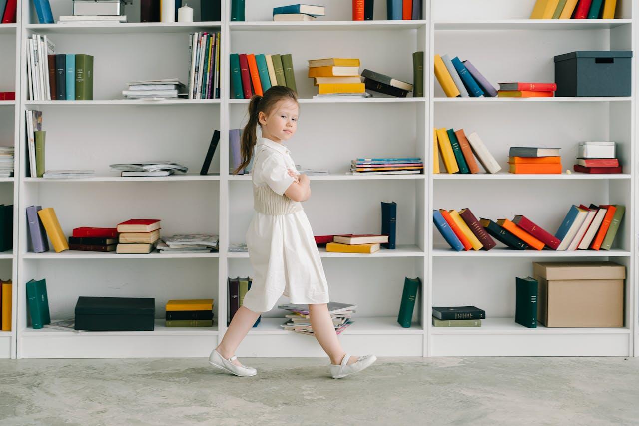 jeune fille en robe blanche marchant devant un rayon de la bibliotheque