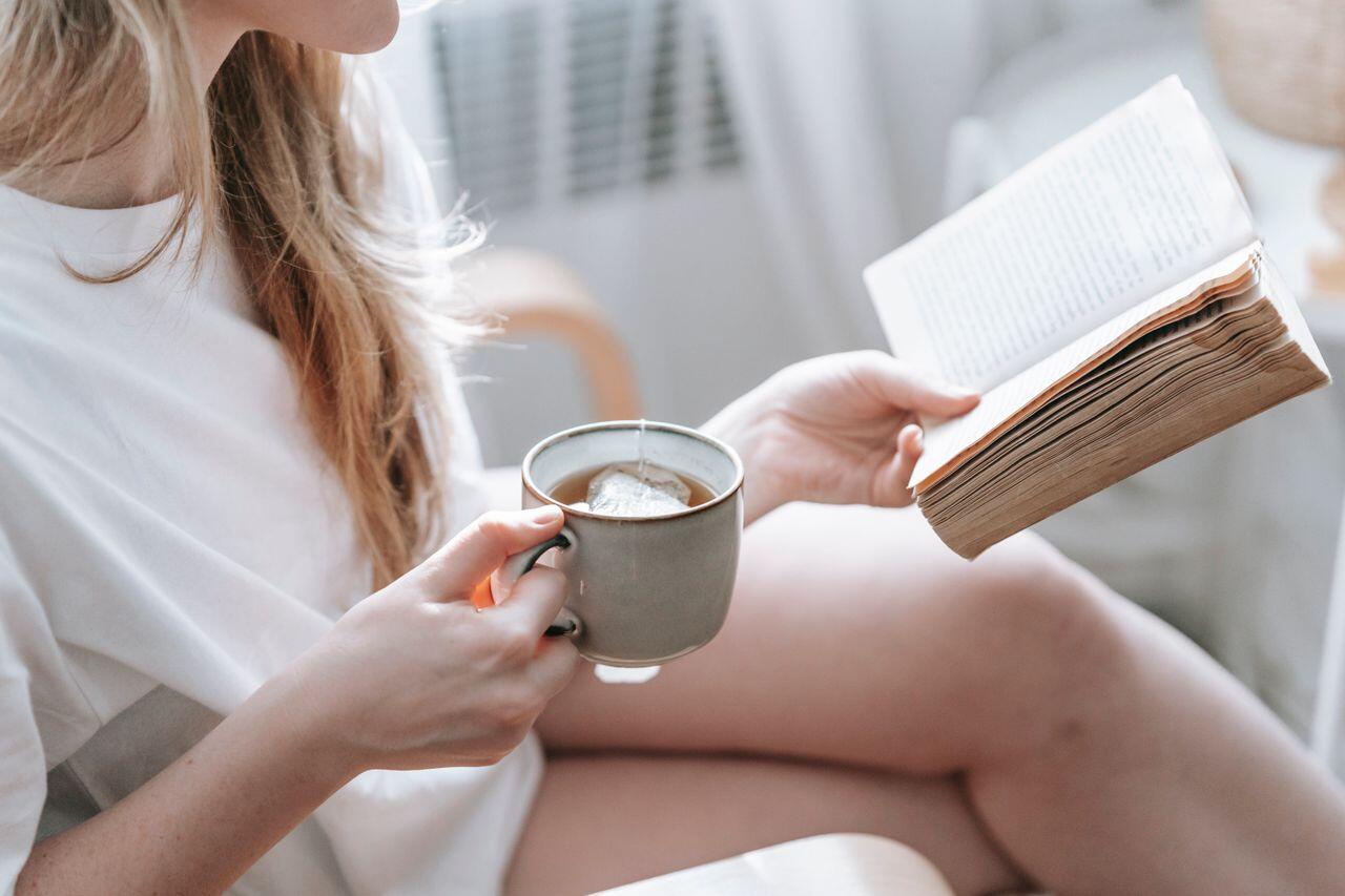 jeune femme chez elle coocooning avec son chocolat chaud lisant un livre