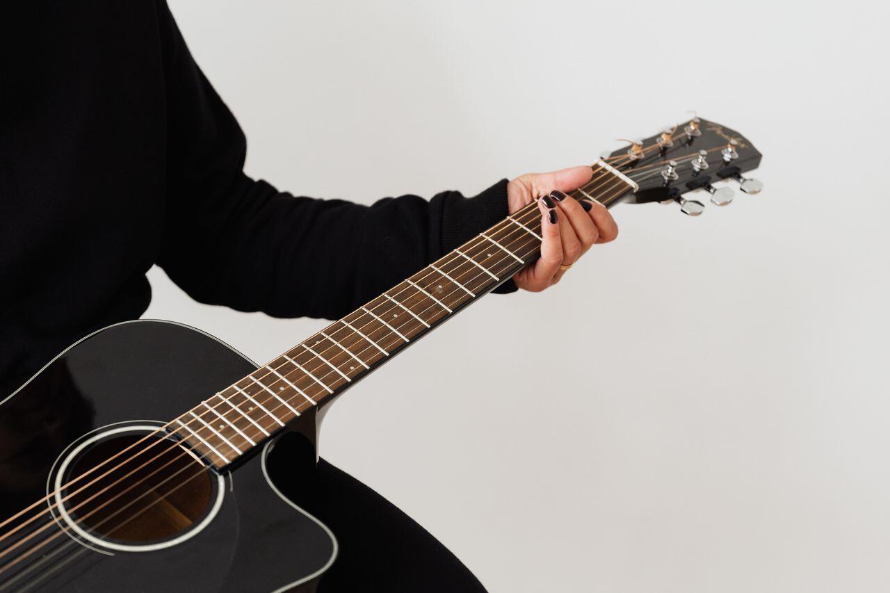 humain en noir assis tenant sa guitare