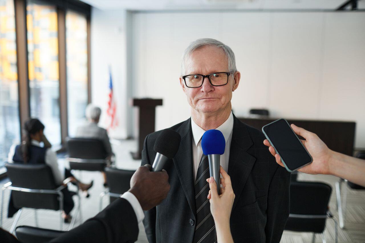homme age a lunettes repondant aux questions des medias
