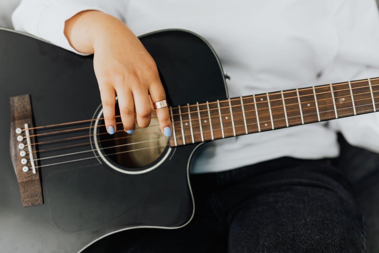 femme manucure bleu jouant de la guitare noire