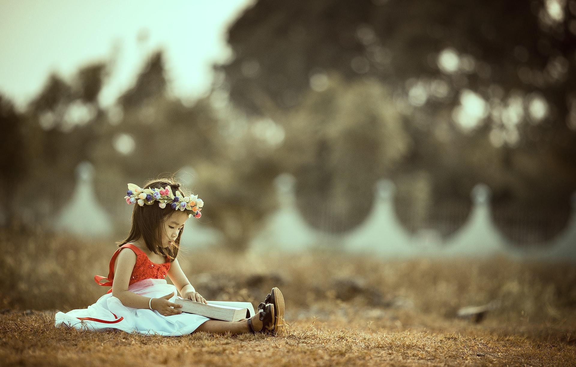 petite fille assise sur le sol et lisant un livre