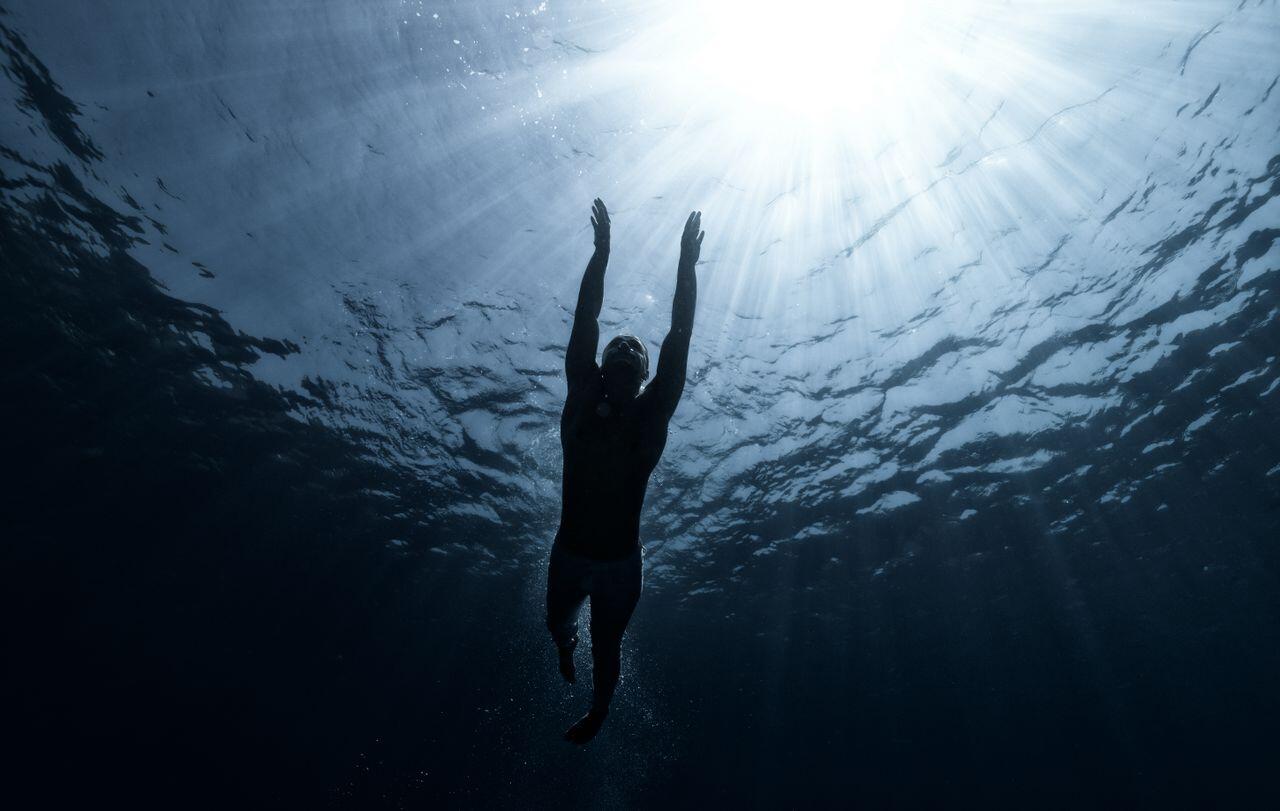 homme nageant sous l eau a la lueur du soleil