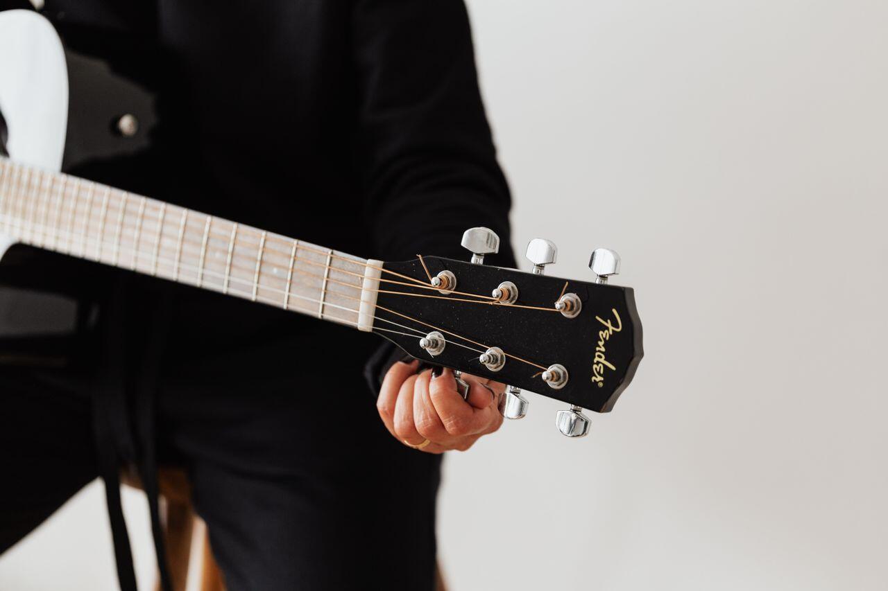 homme en noir accordant sa guitare