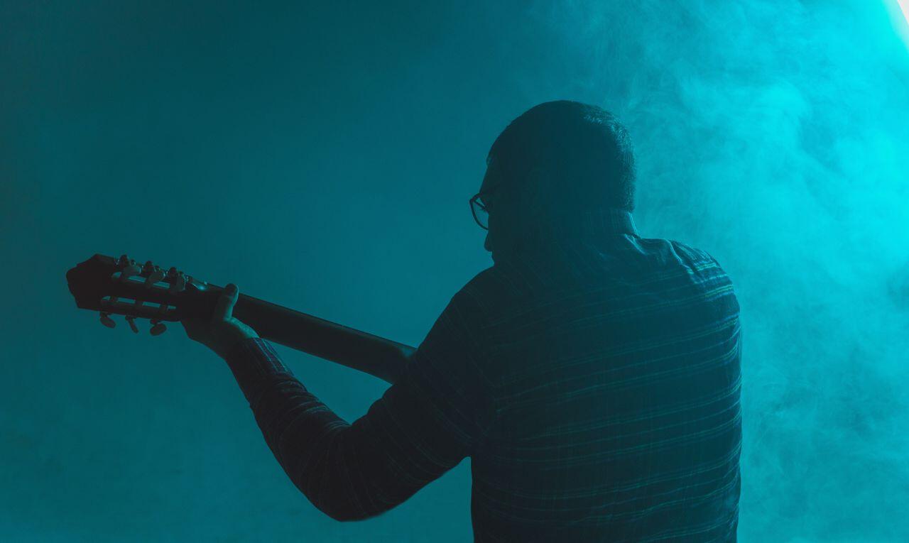 homme sur scene avec sa guitare et lumiere bleue