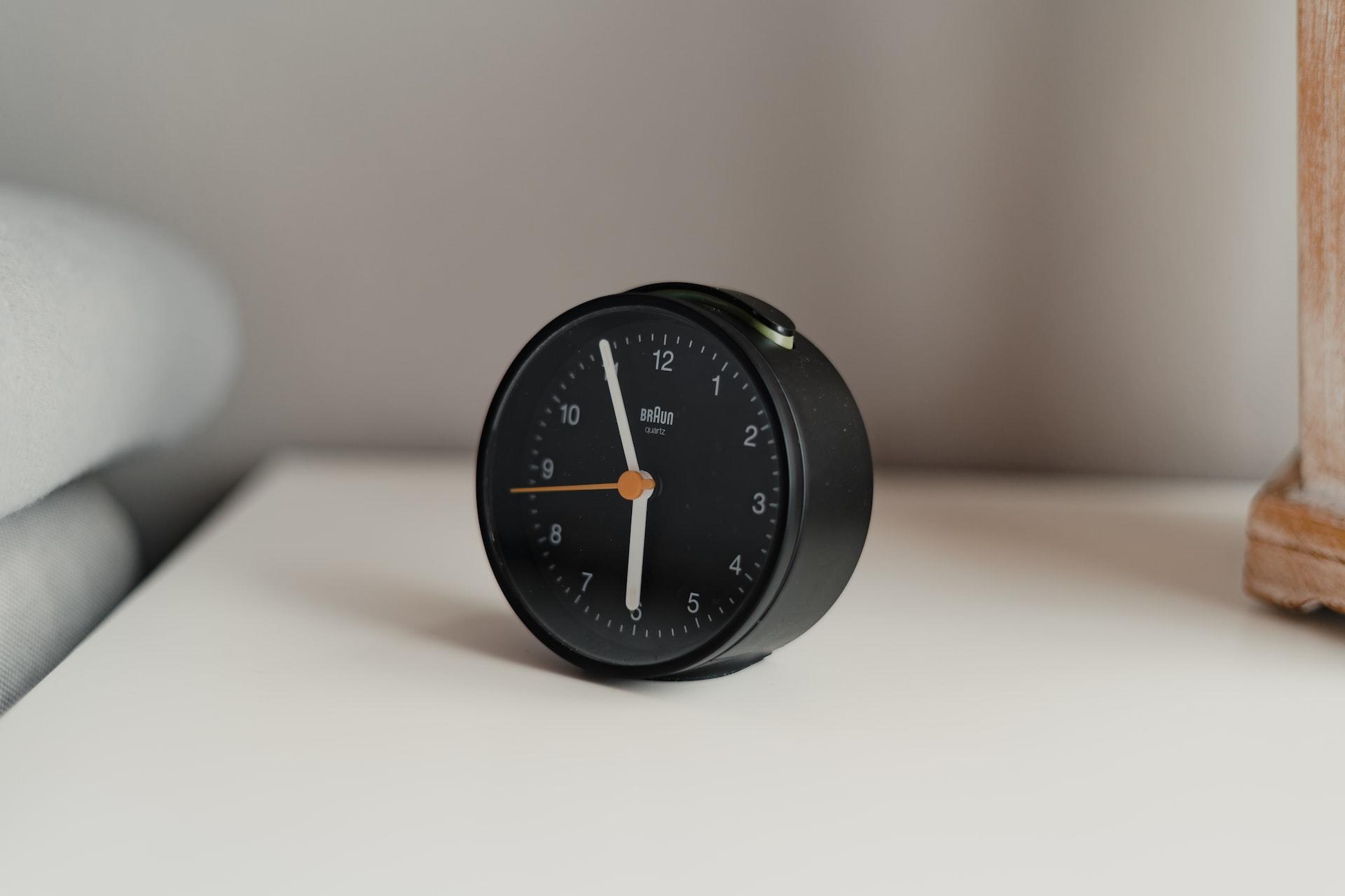 réveil noir horloge près d'un lit
