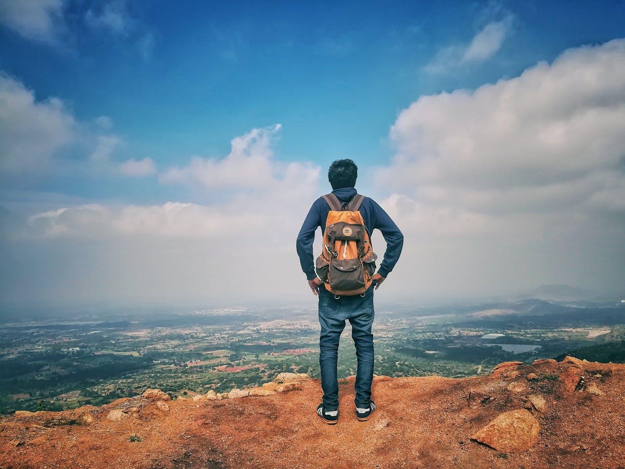 homme avec sac a dos en haut d une falaise
