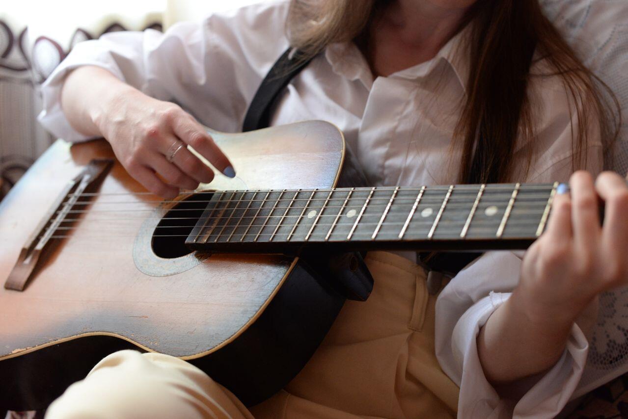 fille en chemise blanche avec sa guitare