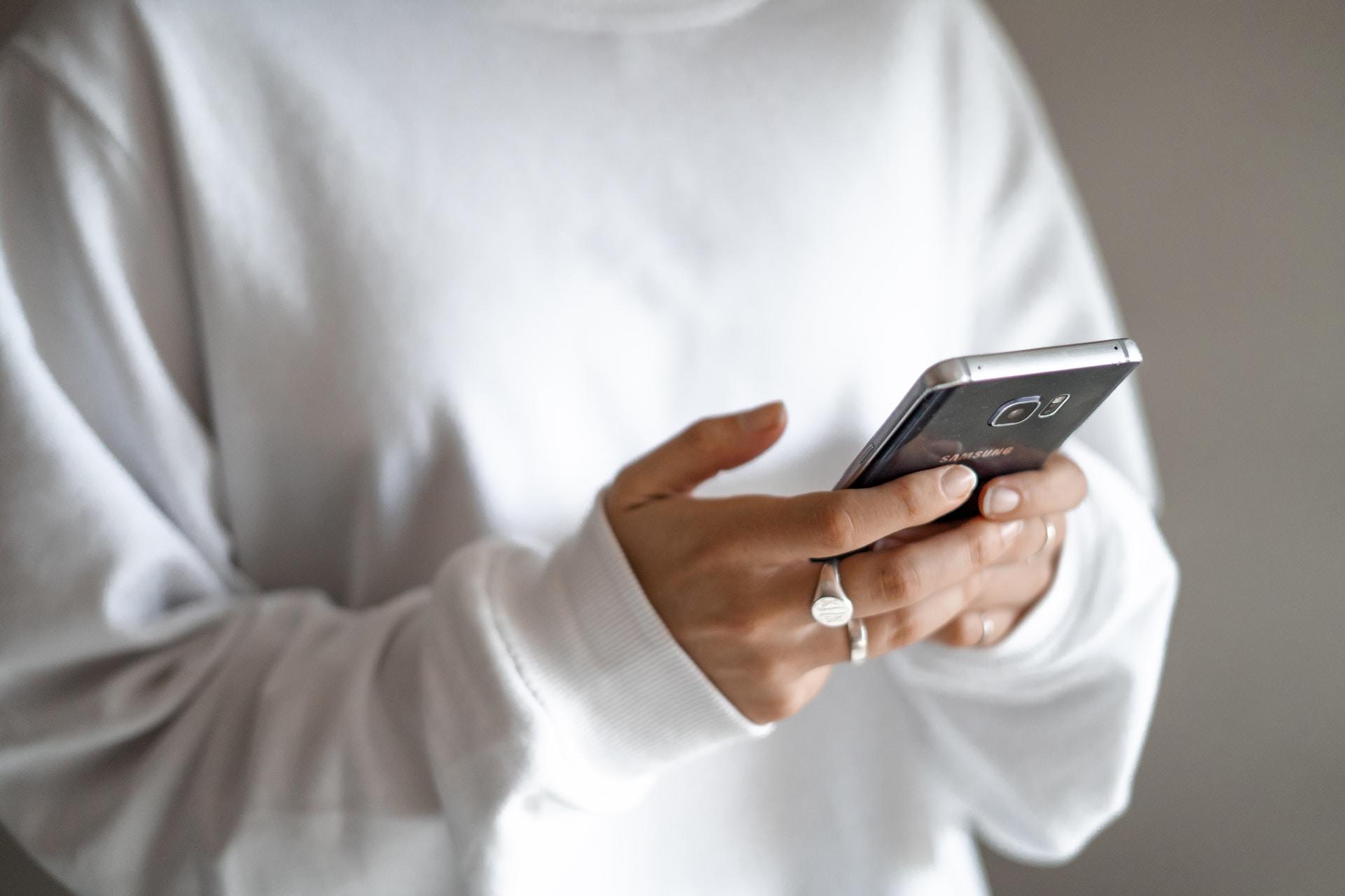 jeune femme tenant dans ses mains un téléphone portable