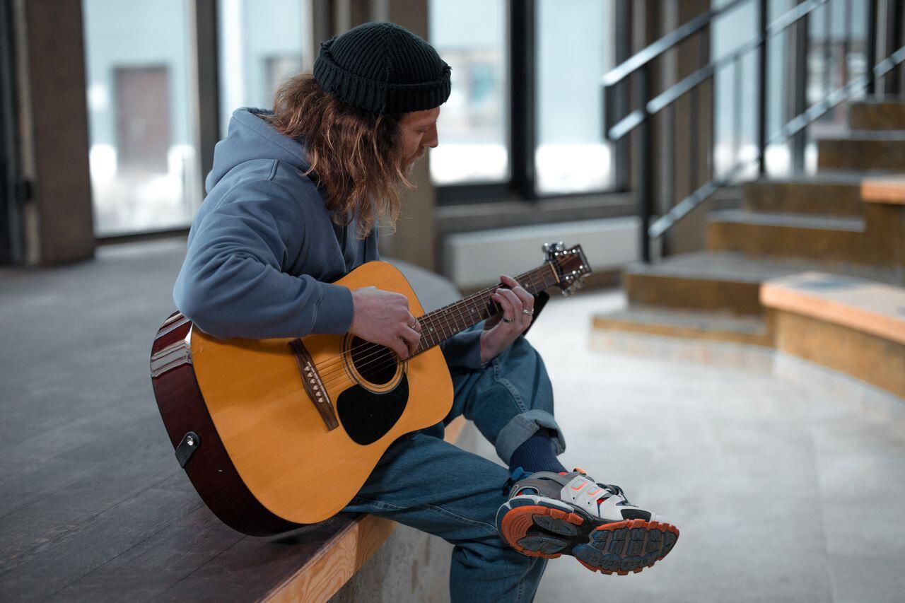 homme avec sa guitare assis a des marches