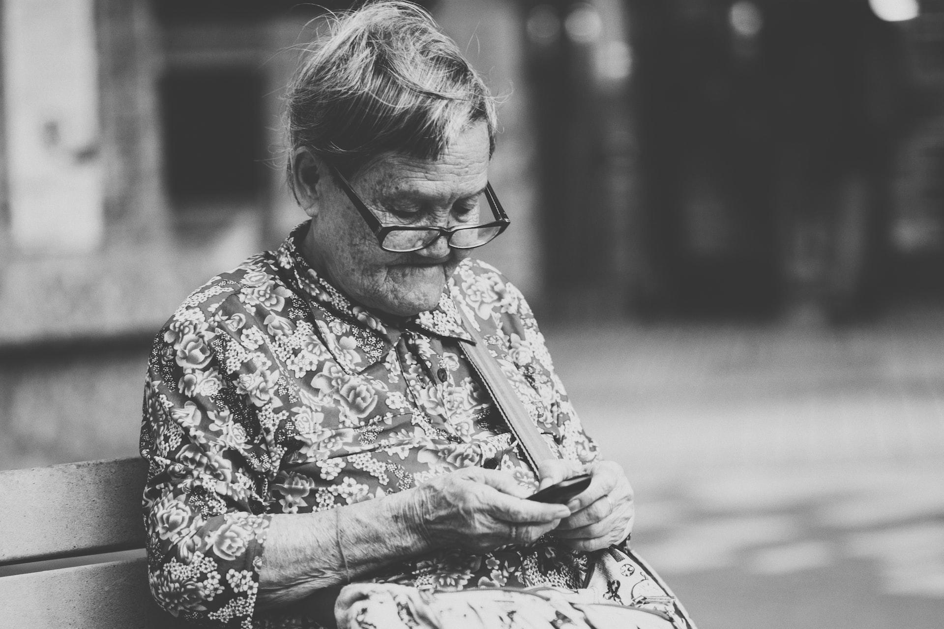 dame âgée sur un banc avec son portable