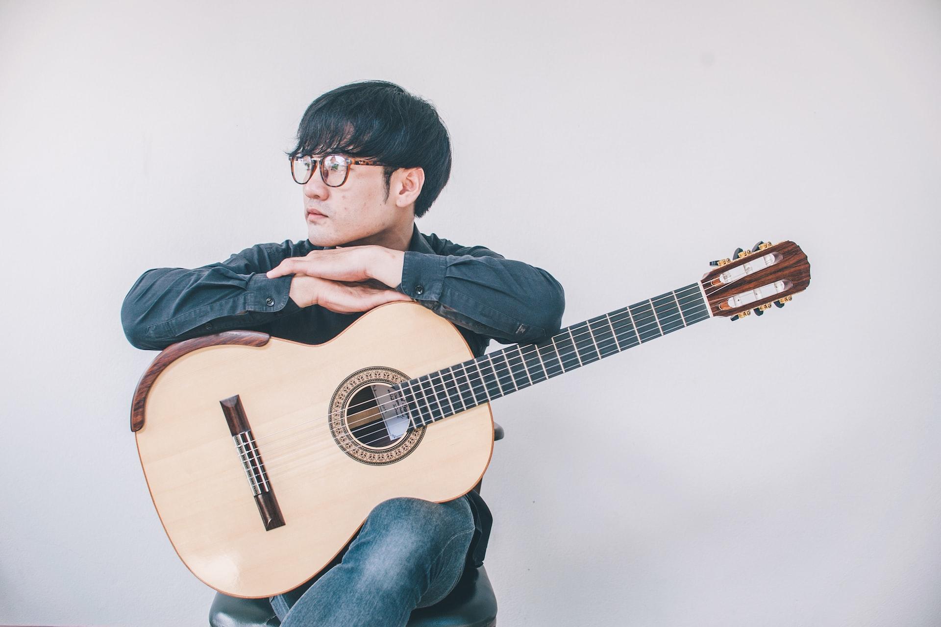 homme tenant une guitare classique avec cordes en nylon