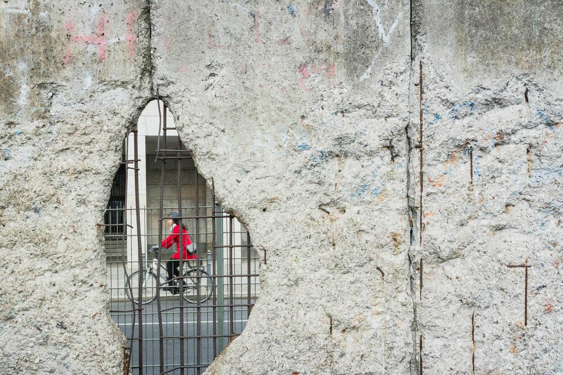 femme en vélo derrière le mur de Berlin