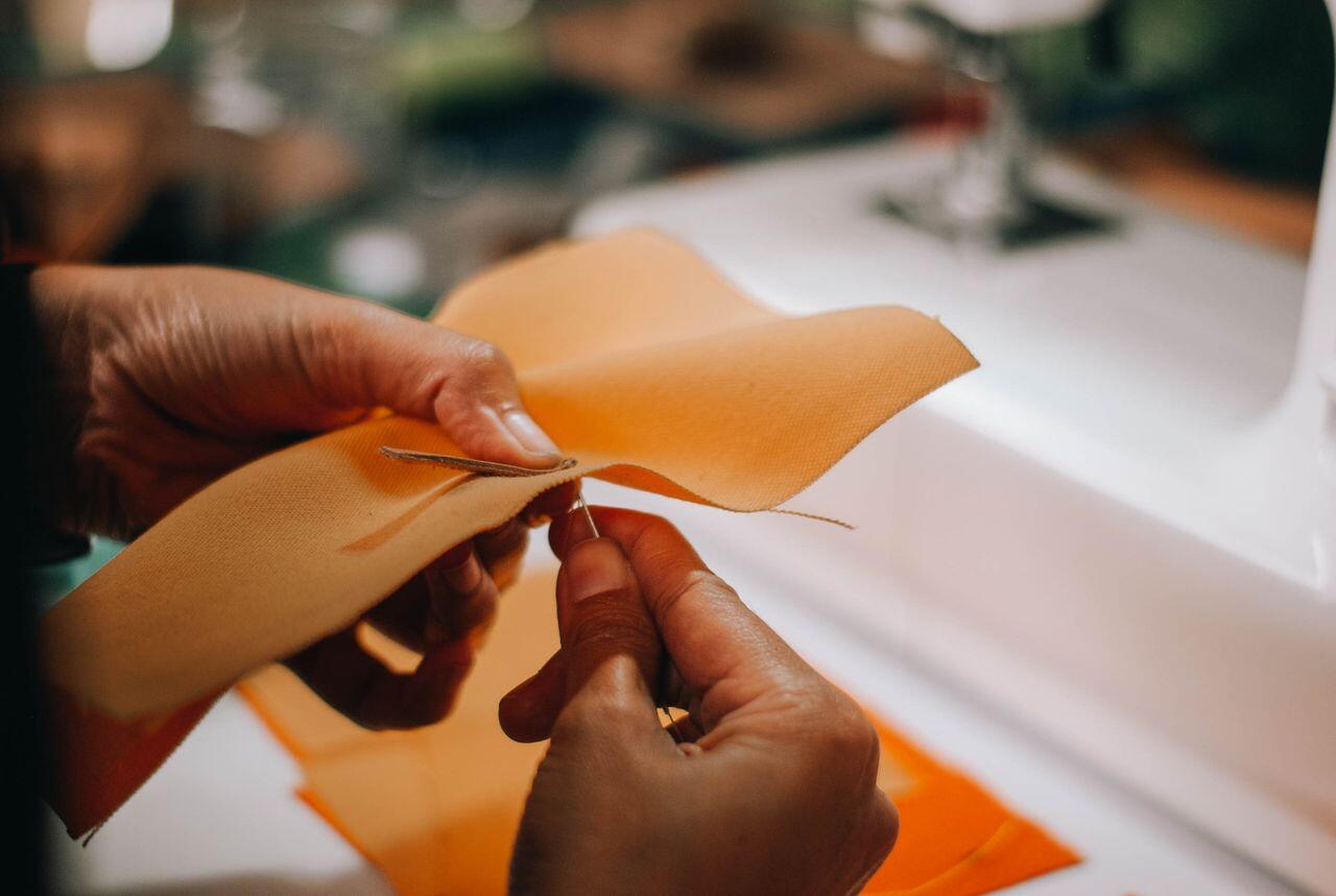 mains cousant un tissu orange