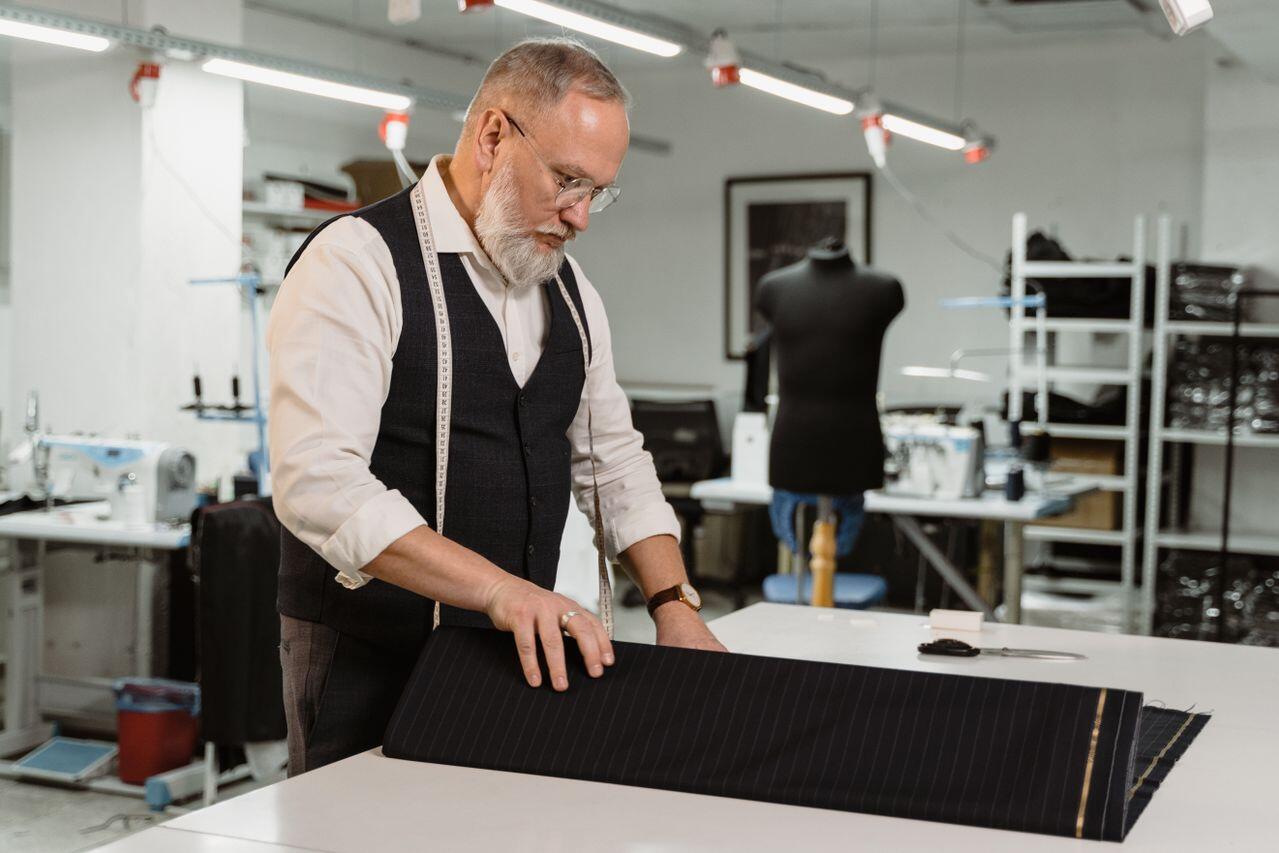 homme couturiel en train de mesurer un patron sur une table