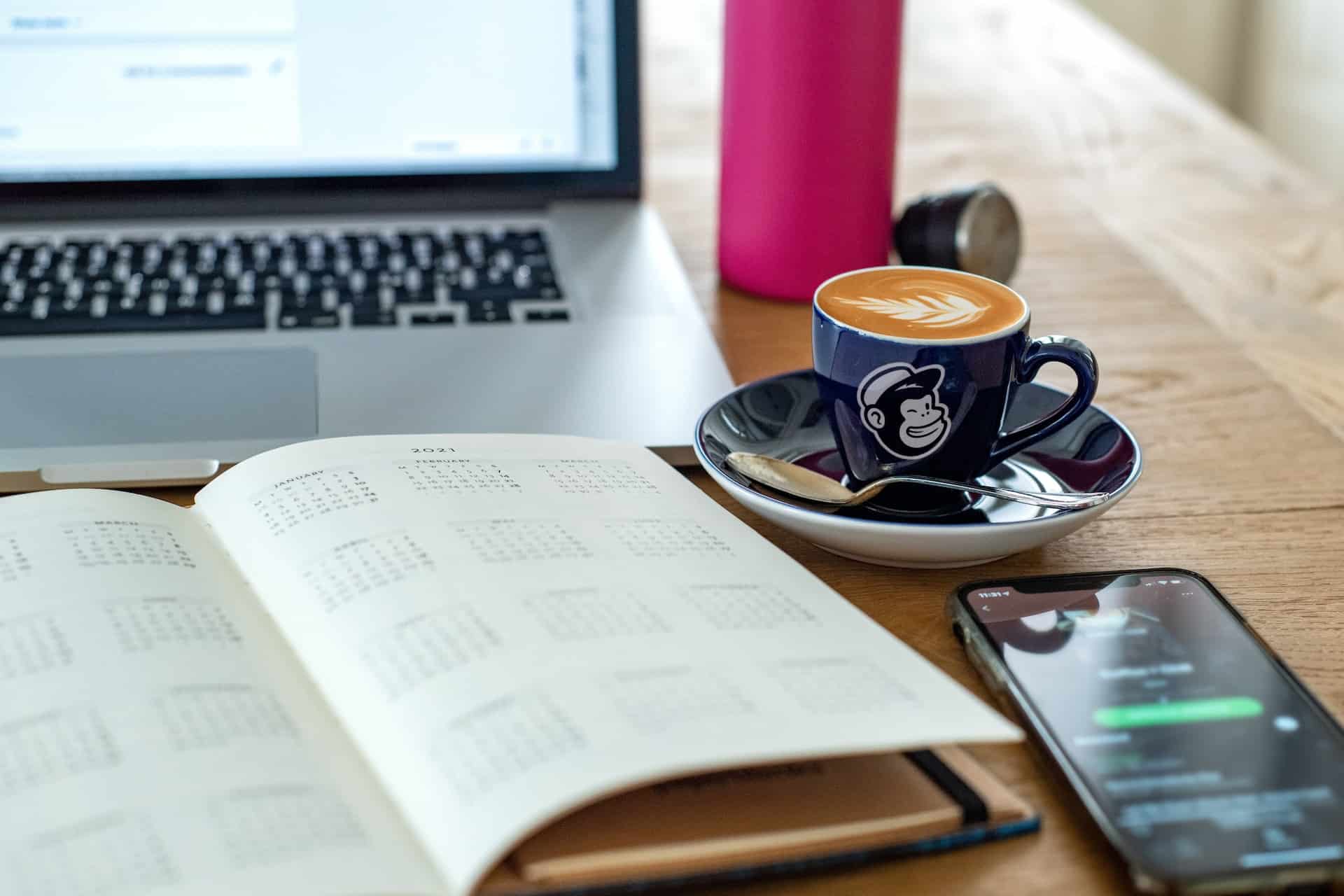 carnet smartphone et cafe devant un laptop sur une table