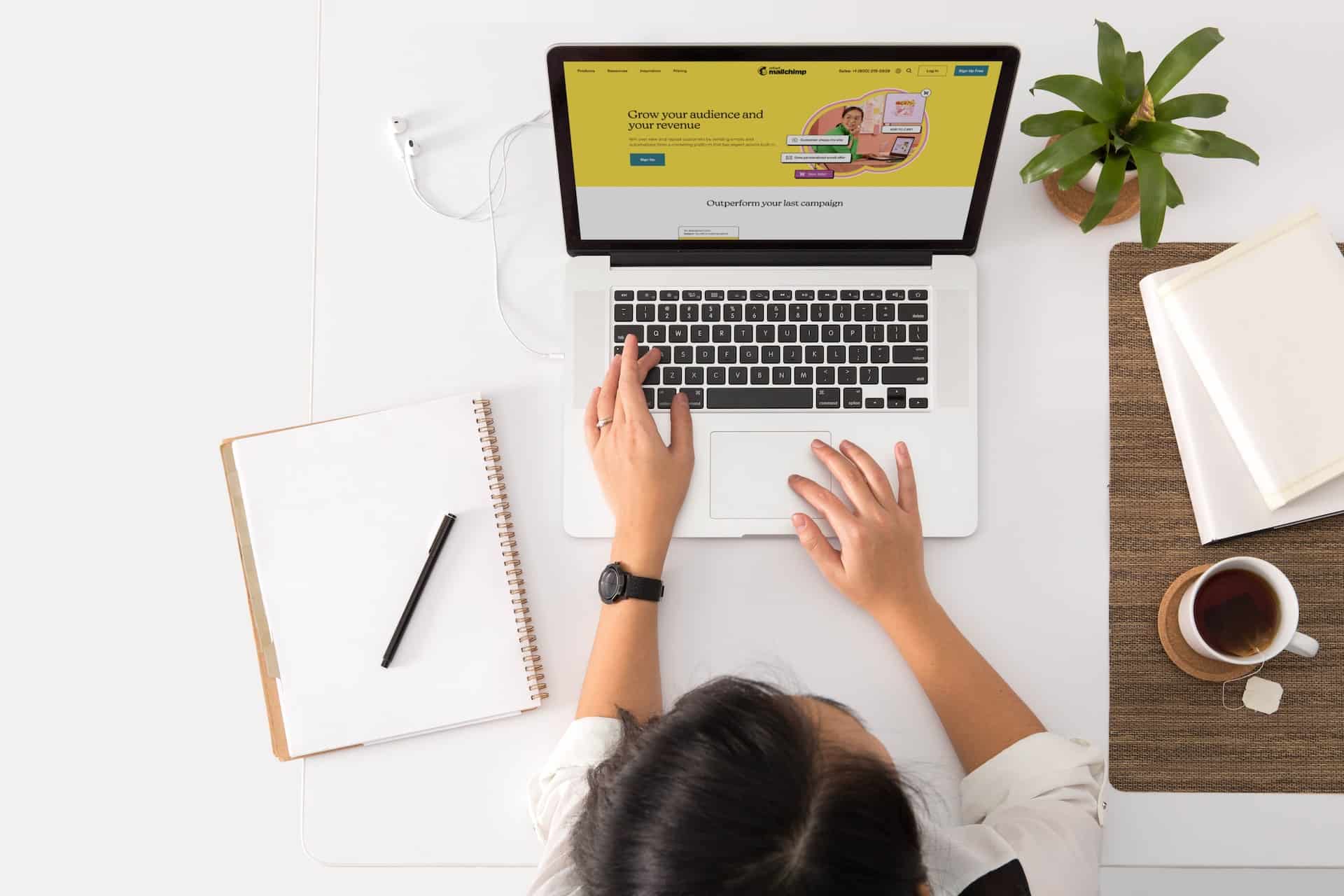 jeune femme travaillant sur son laptop avec un cafe et un carnet a cote