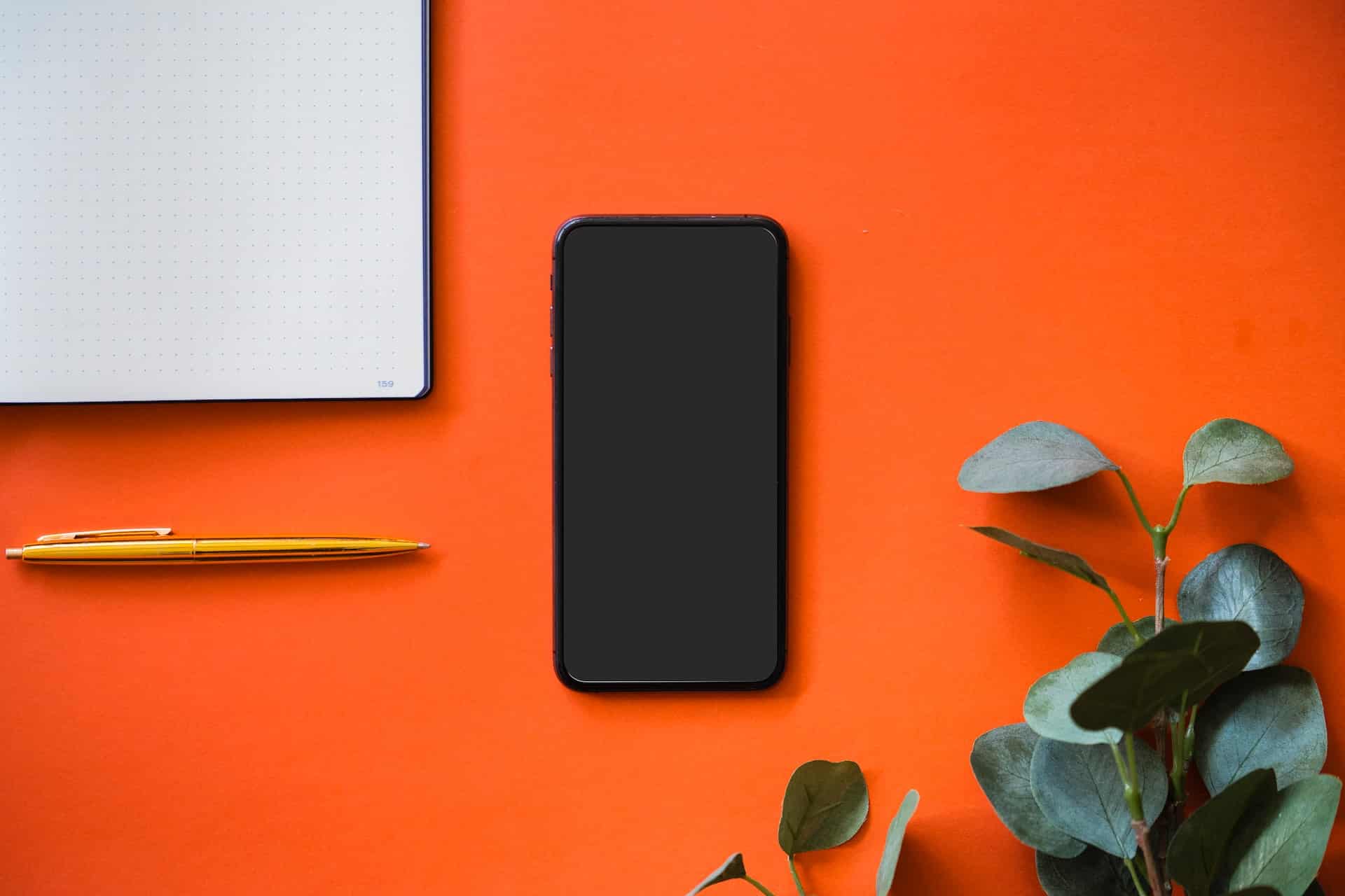 smartphone et carnet sur un fond orange