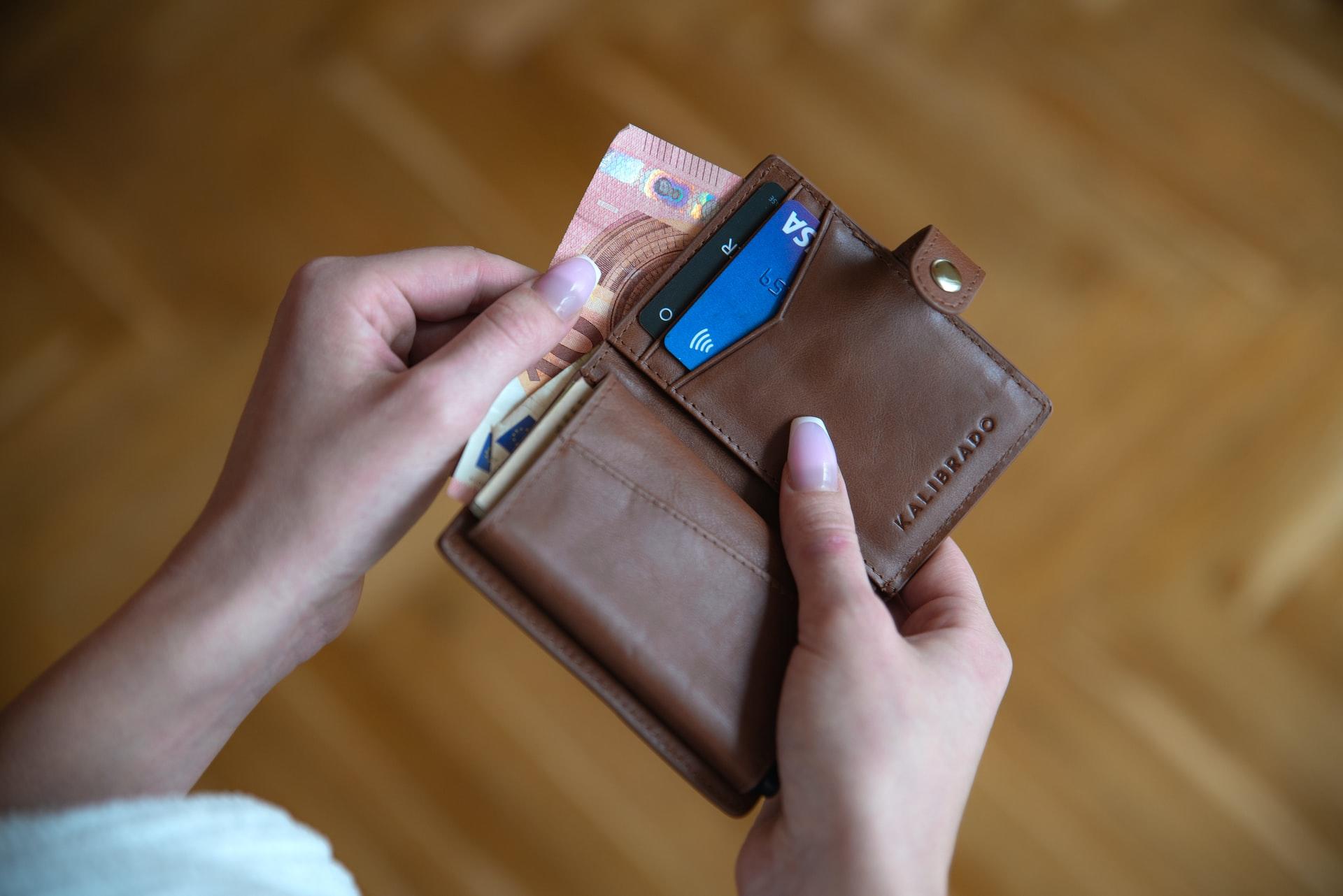 mains d'une femme ouvrant son portefeuille