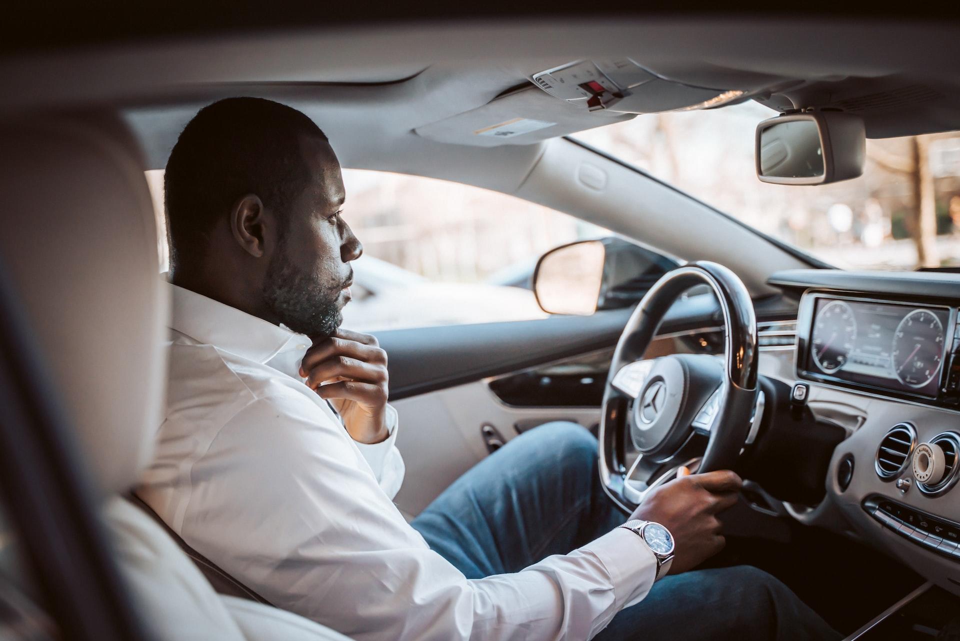homme au volant d'une voiture sur la route