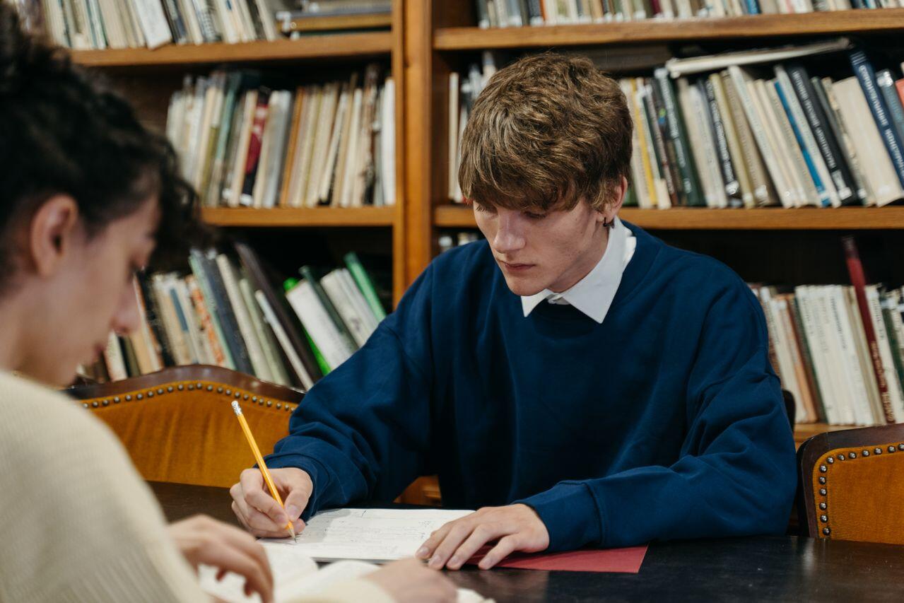jeune homme en train d etudier a la bibliotheque