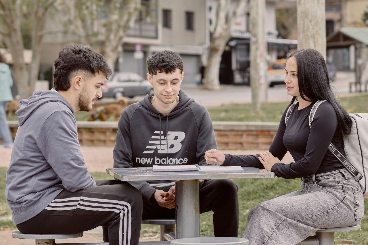 trois jeunes assis a une table en exterieur