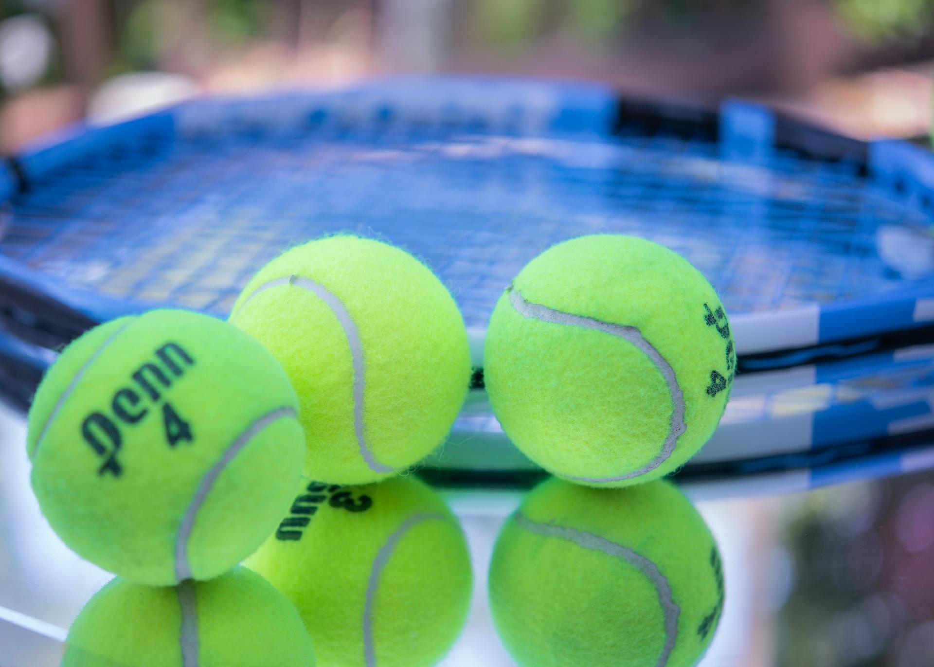 balles de tennis à côté d'une raquette