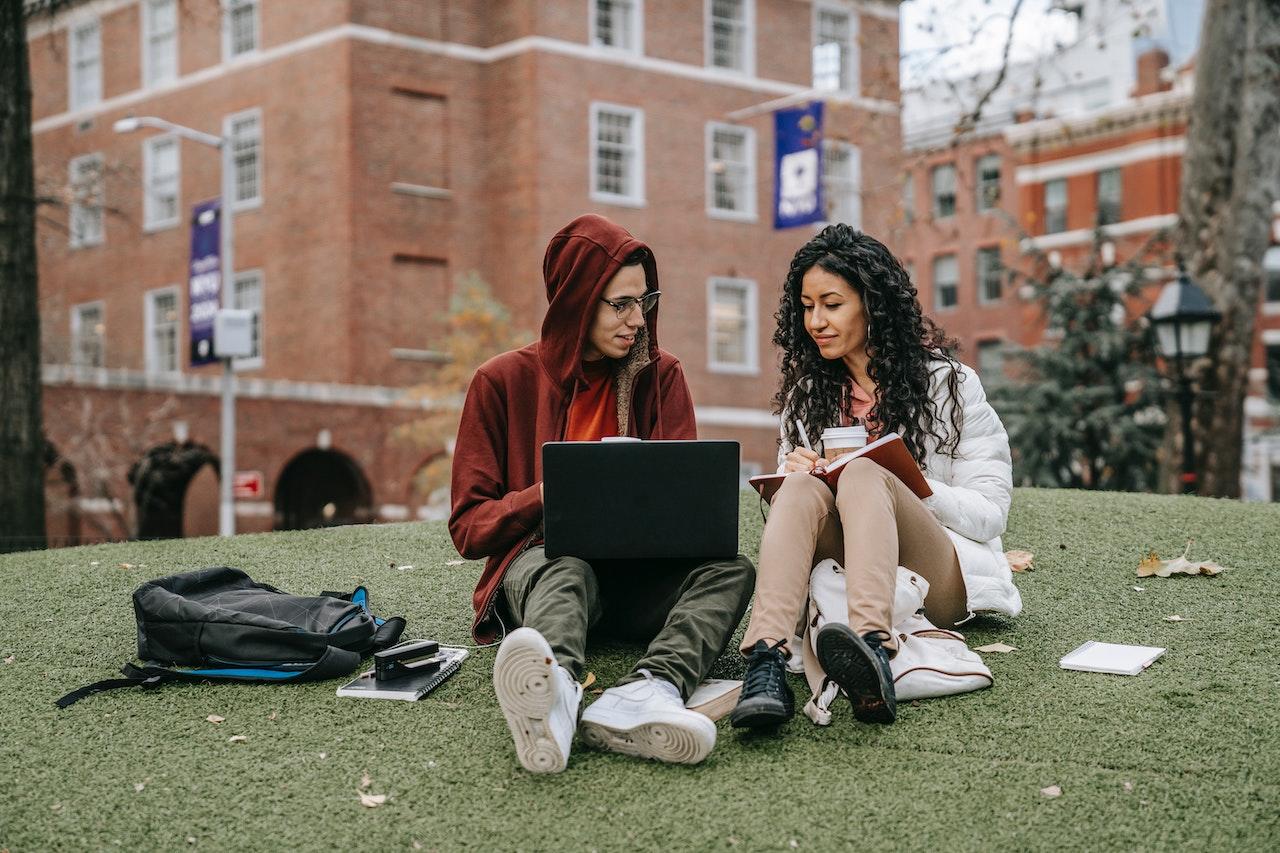 Deux etudiants assis sur l herbe devant leur universite
