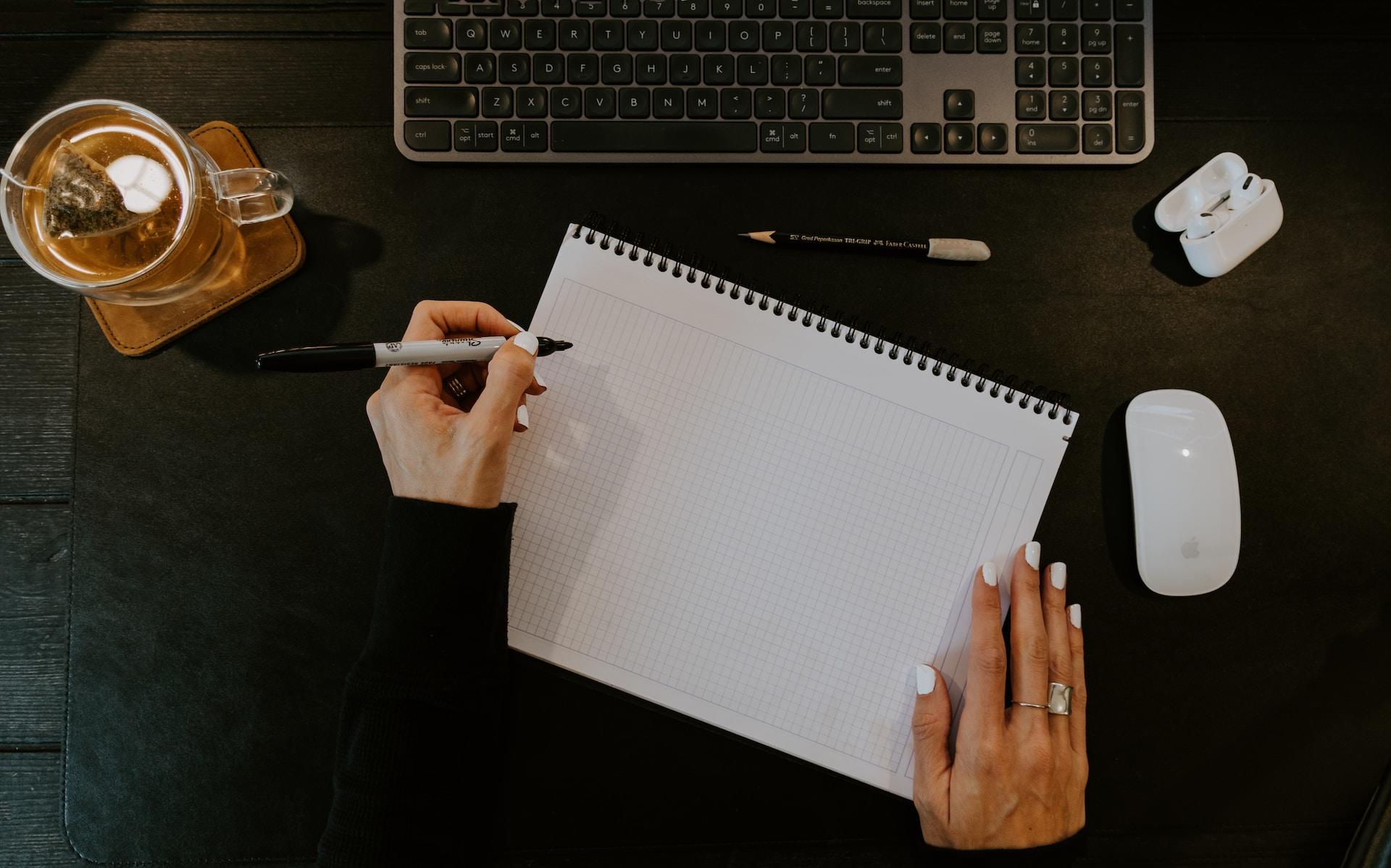 main de femme tenant un crayon sur son bureau pour écrire