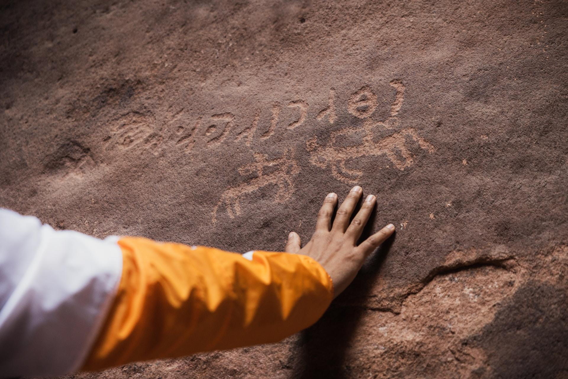 main posée sur une grotte avec des dessins historiques