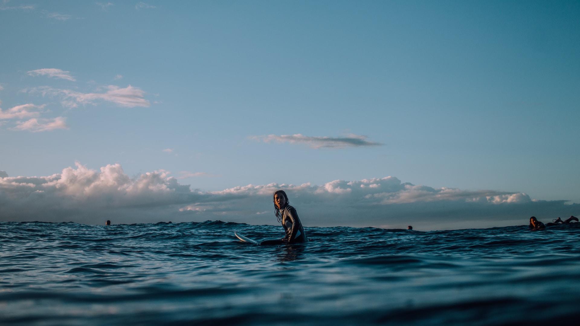 femme avec son surf dans les vagues