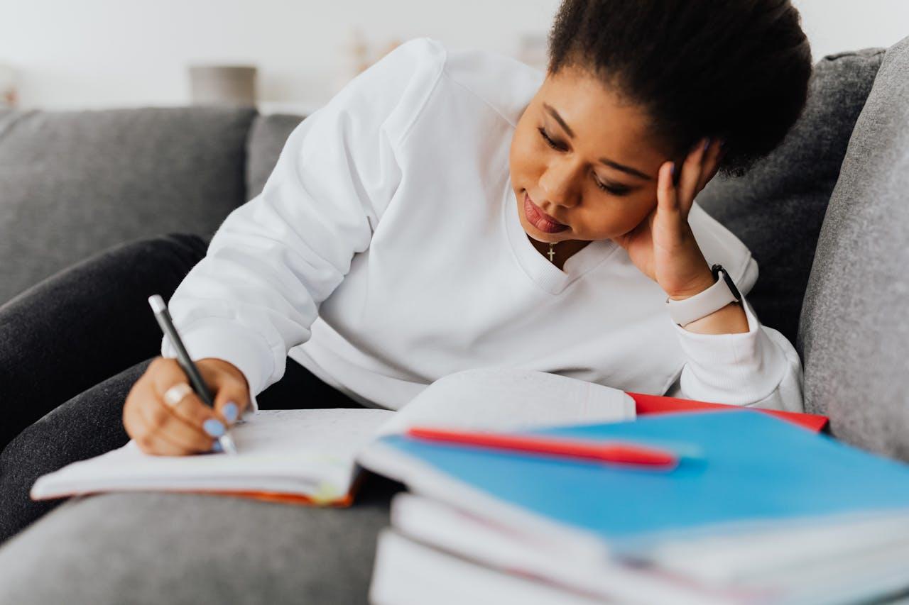 jeune femme se tenant la tete et travaillant avec ses cahiers