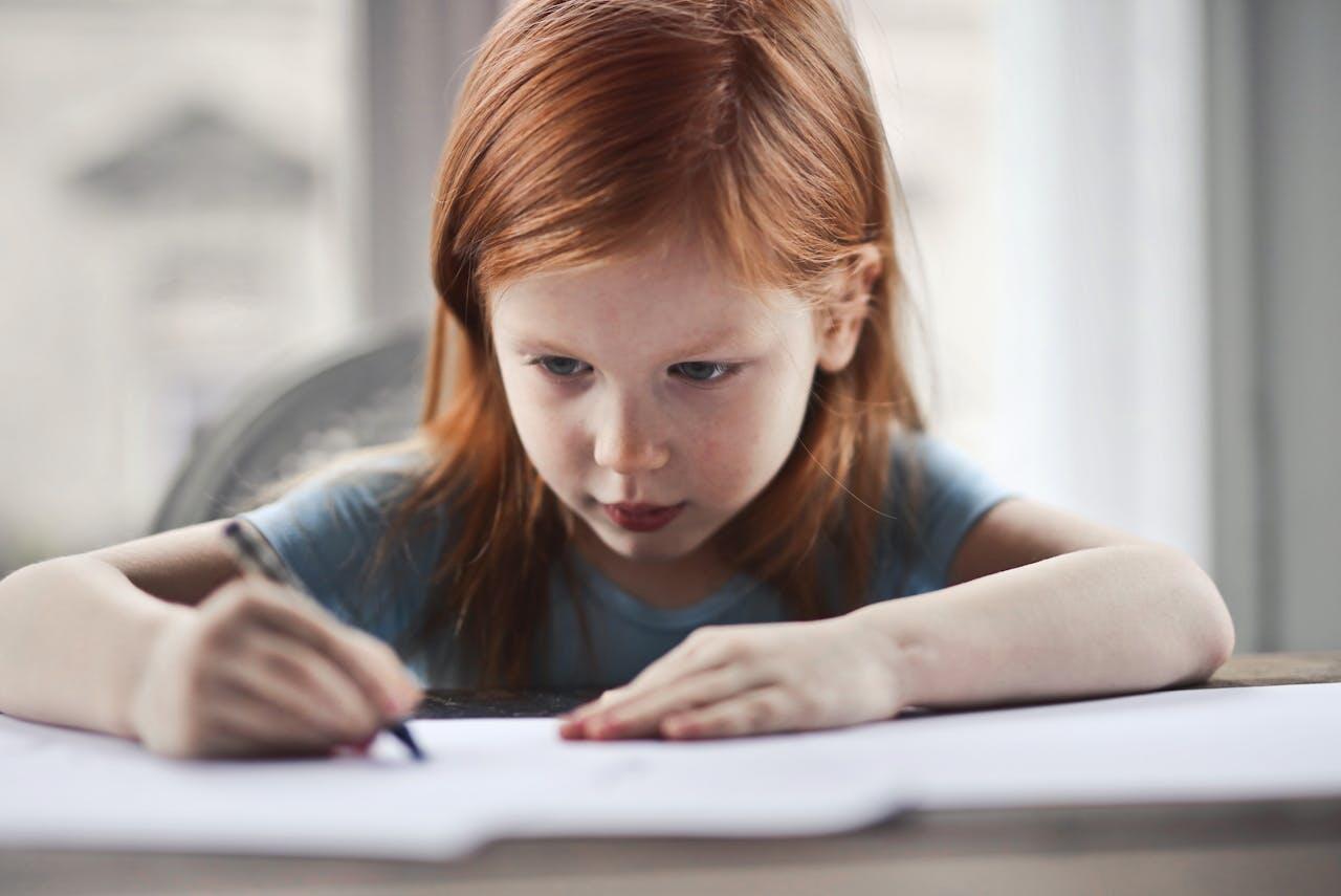 petite fille rousse faisant ses devoirs