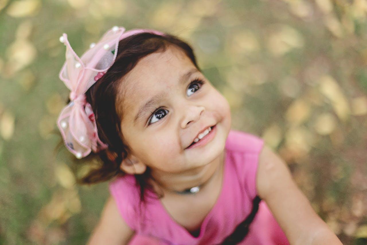 petite fille en rose souriant en regardant vers le ciel
